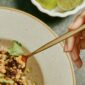 A white hand holds a spoon digging into a delicious vegan meal from Purple Carrot. The meal primarily features beans, a great source of plant based protein.