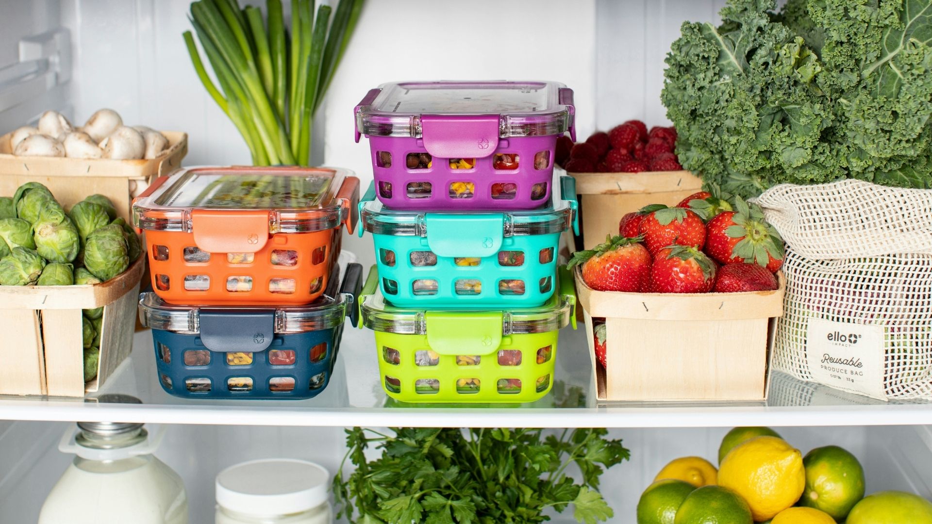 Containers of prepared food and fresh produce sit inside a fridge shelf. The produce is fresh.