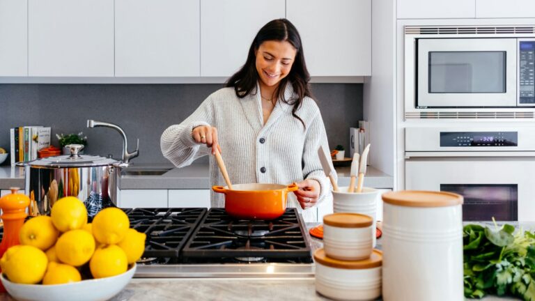 A woman stands in her kitchen cooking plant-based substitutes for meat protein like tofu and seitan.